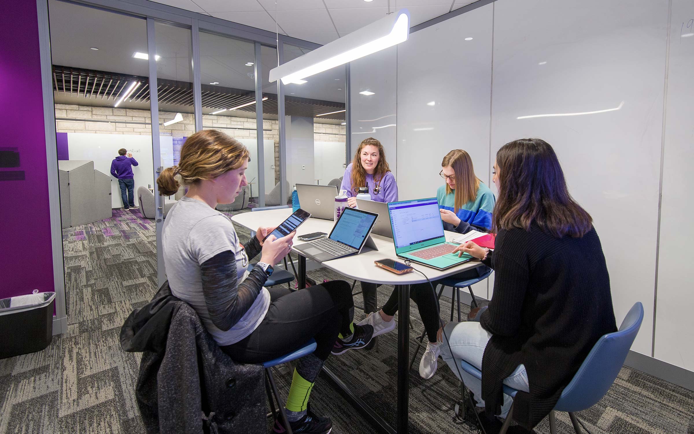 Students with laptops in collaboration room.